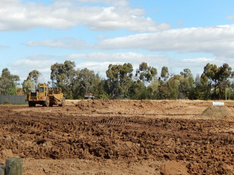 A red car is Parked next to a large Yellow Bulldozer — Mawson Constructions in Kialla, VIC