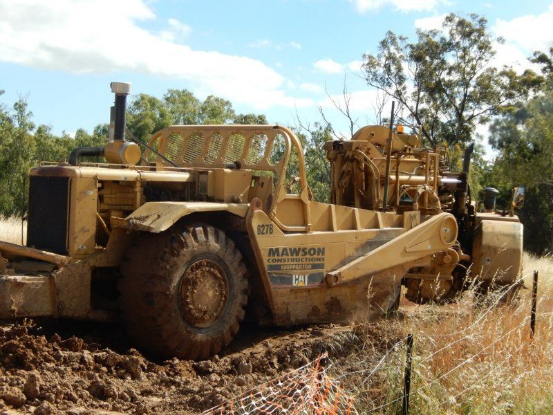 A Bulldozer is Driving down a dirt road with trees in the Background — Mawson Constructions in Kialla, VIC