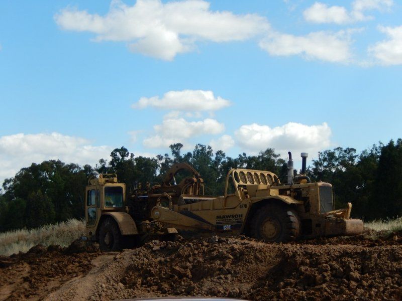 A Manson Bulldozer is Driving down a dirt road — Mawson Constructions in Kialla, VIC