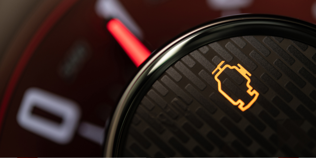 Close-up of illuminated check engine light on a car dashboard.