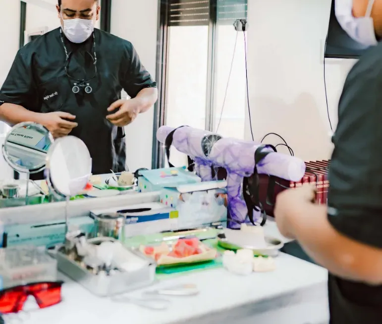 Dr omar prépare son matériel sur un espace de travail équipé de miroirs, d'instruments dentaires et de fournitures médicales.