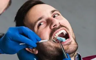 Un dentiste utilise un miroir dentaire et un rouleau de coton pour examiner les dents d'un patient dans un cabinet dentaire.