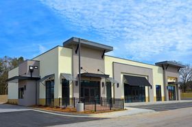 Modern beige commercial building with black awnings and large windows under a blue sky