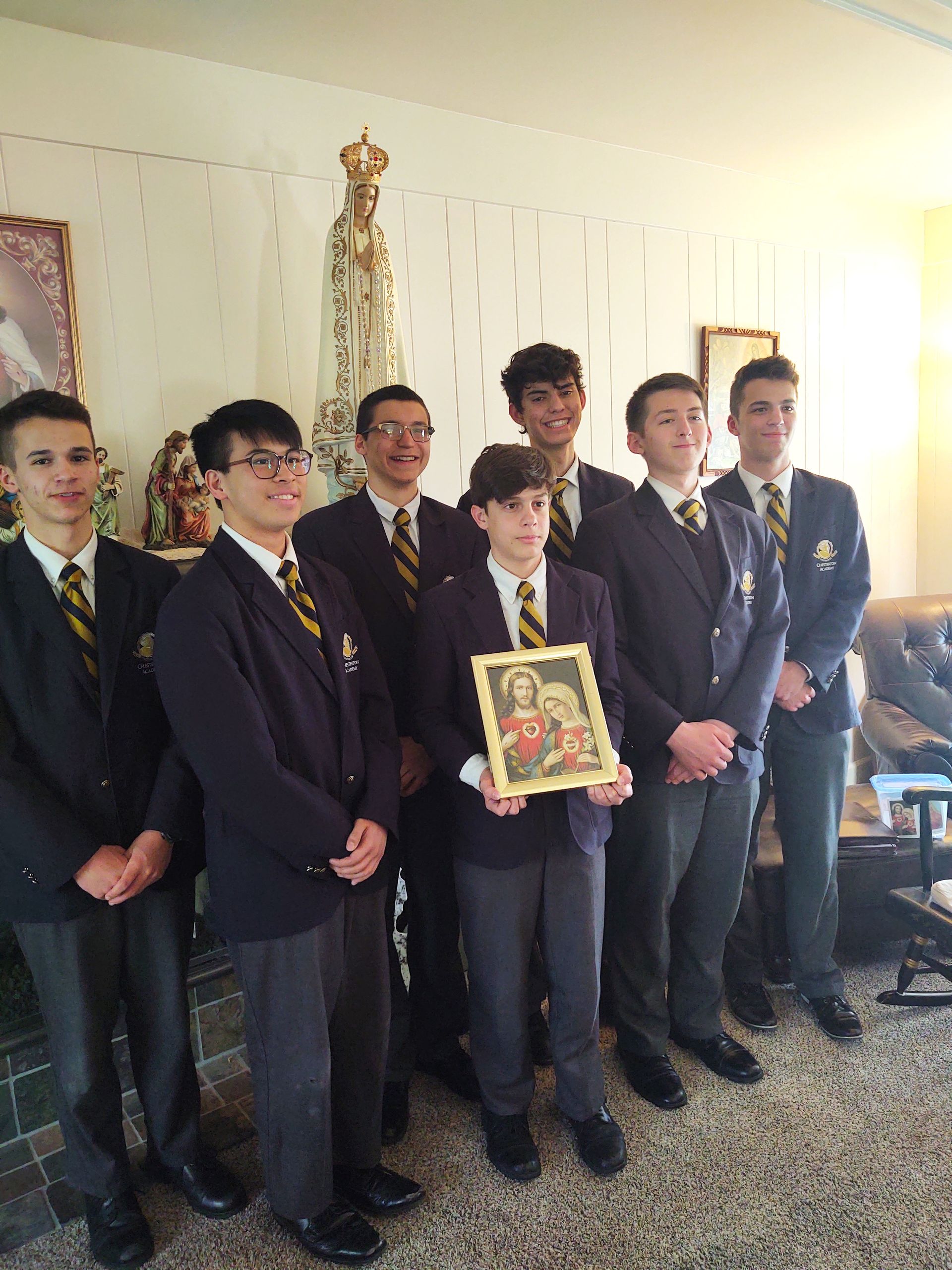 A group of young men in suits and ties holding a picture of the sacred heart of Jesus