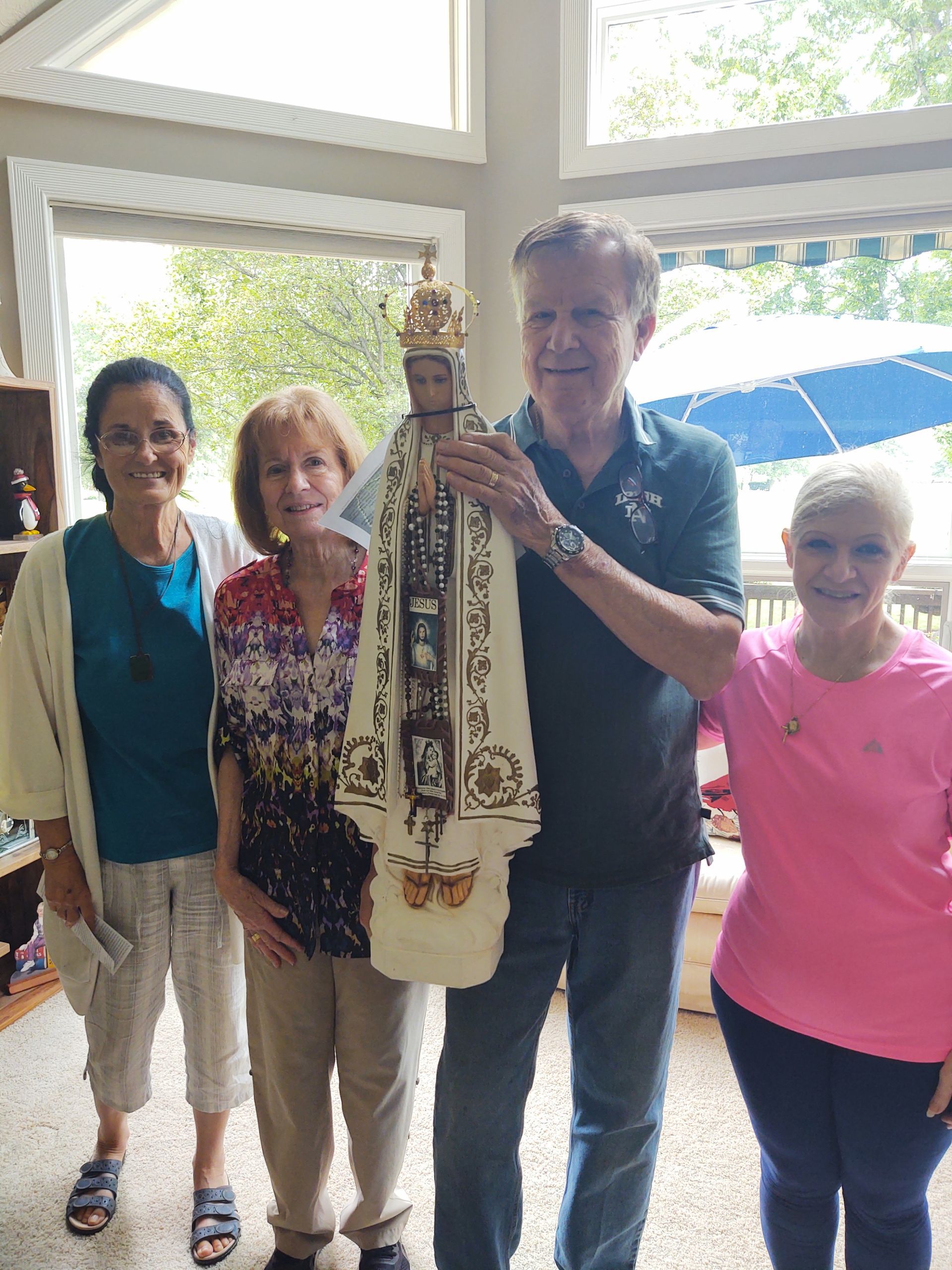 A group of people standing holding a statue of Our Lady of Fatima
