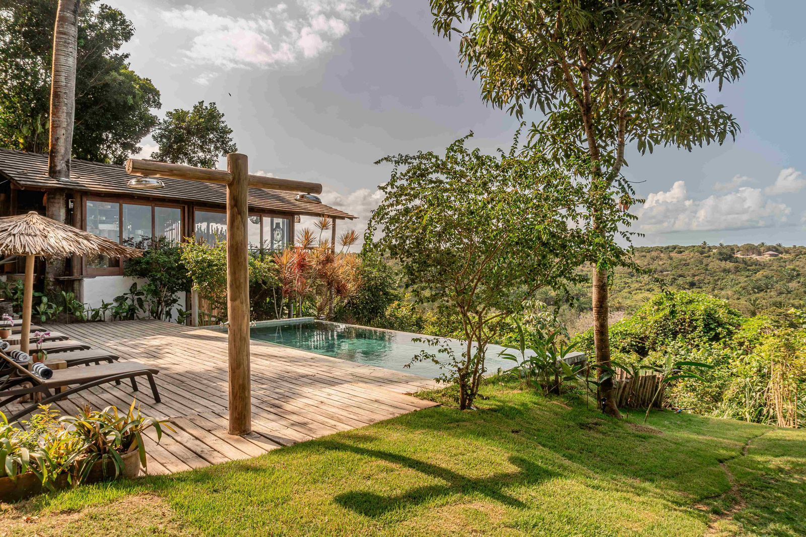 Uma casa grande com piscina no quintal cercada por árvores.