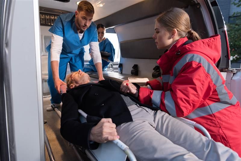 Paramedics loading a senior man into an ambulance on a stretcher.