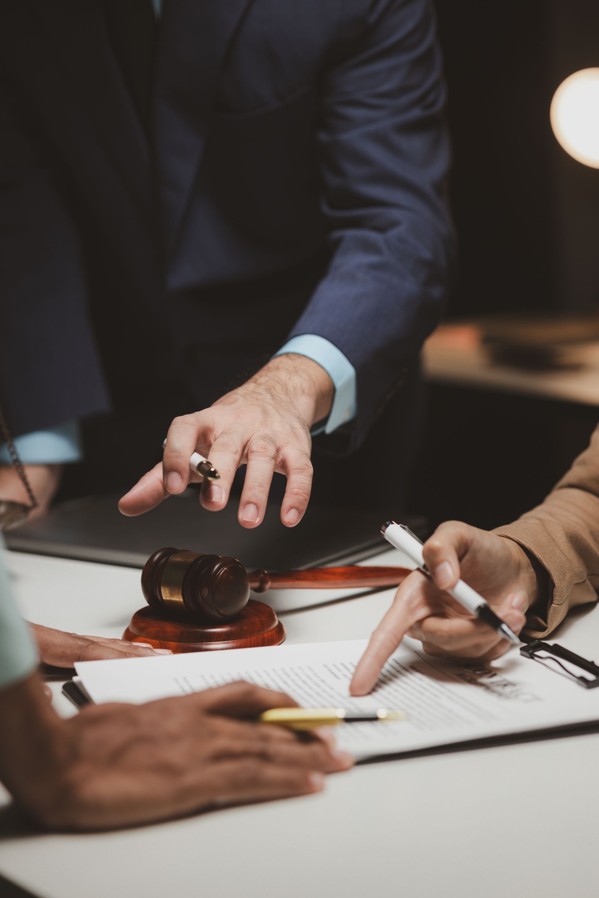 Three people reviewing documents at a table; a gavel sits beside paperwork.