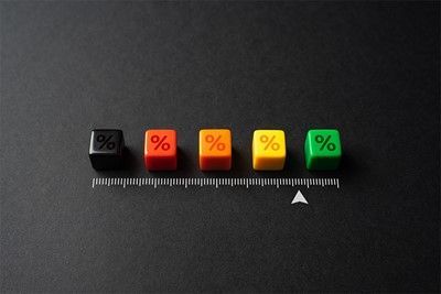 Five colored dice with percentage symbols sit above a ruler, arranged on a dark surface.