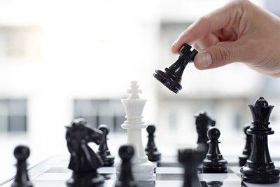 Hand placing black rook near white king on a chessboard.