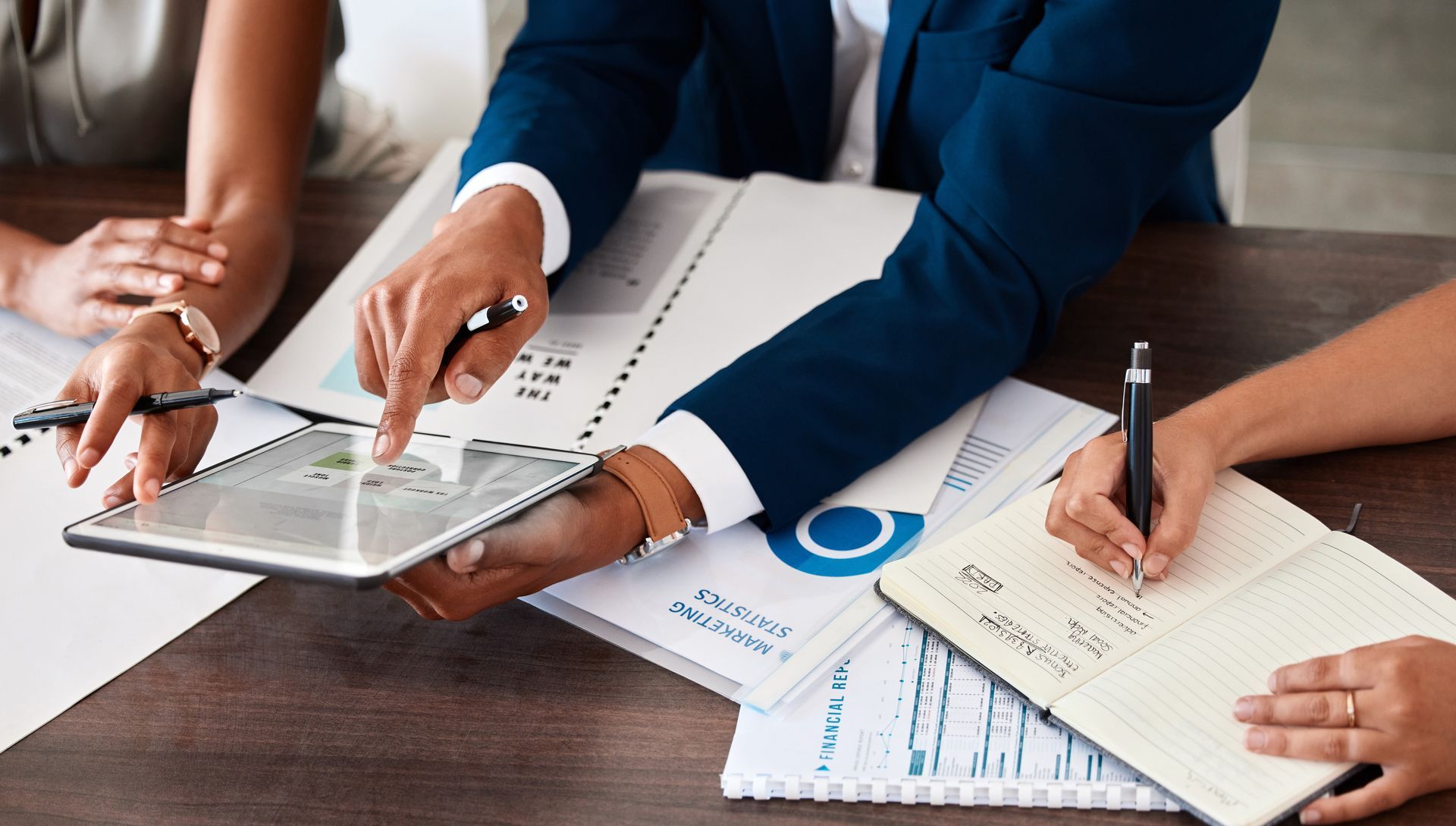 Business people reviewing documents and a tablet during a meeting.