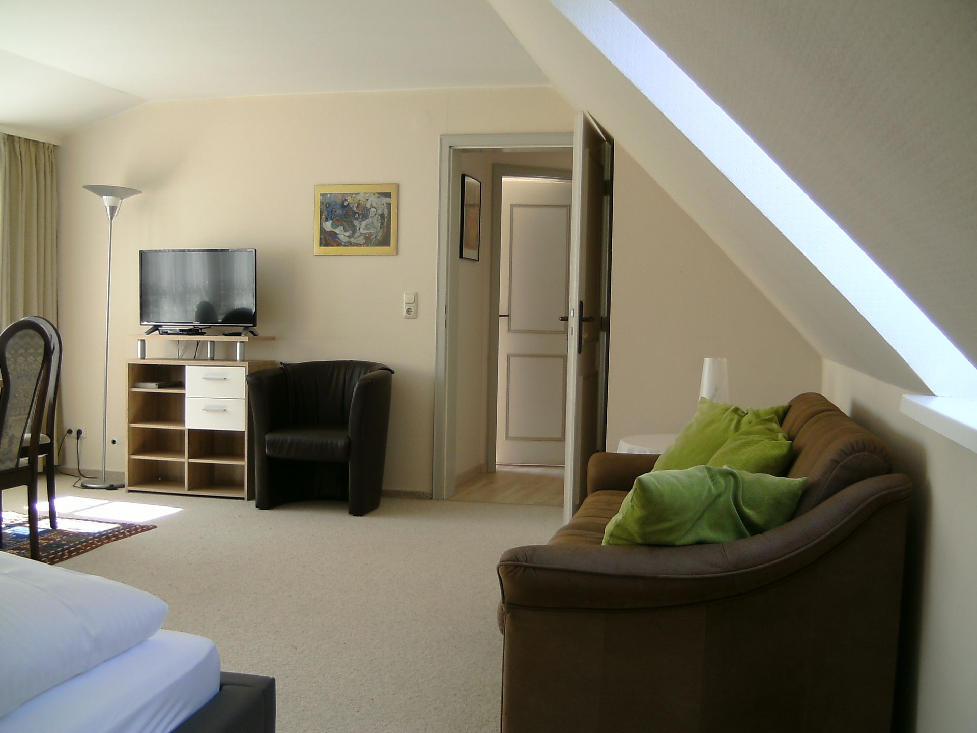 Ein Wohnzimmer mit einer Couch, einem Sessel und einem Flachbildfernseher