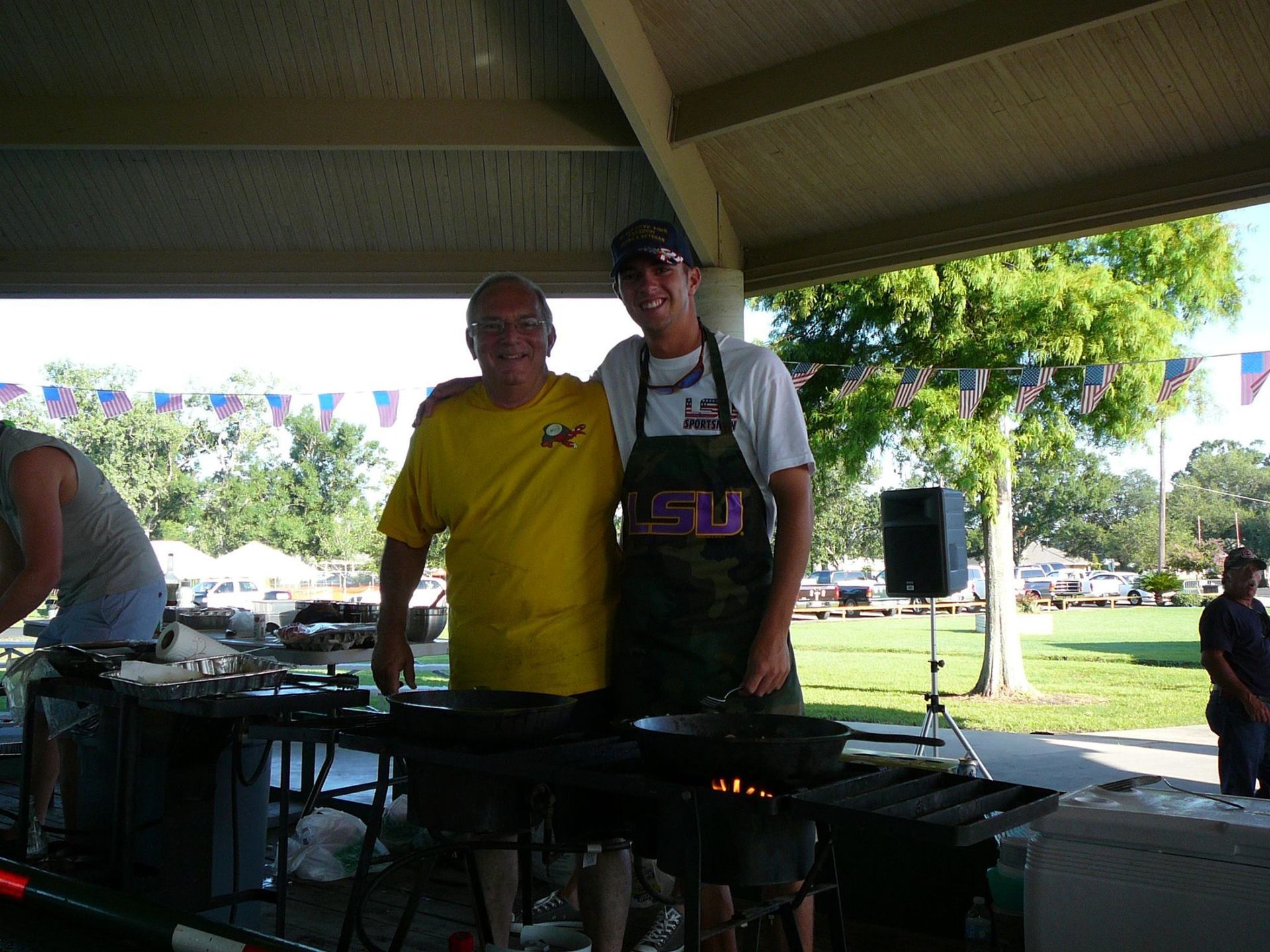 Two men posing for a picture under a pavilion with one wearing an apron that says ' ucsd ' on it