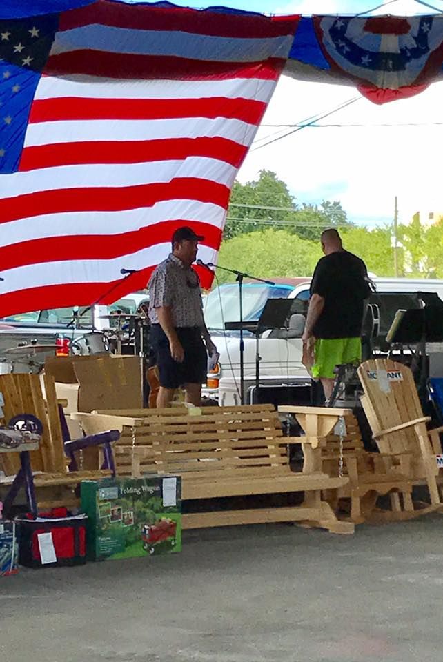 Two men are standing under a large american flag