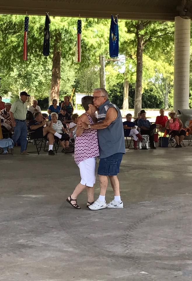 A man and a woman are dancing under a pavilion in front of a crowd.
