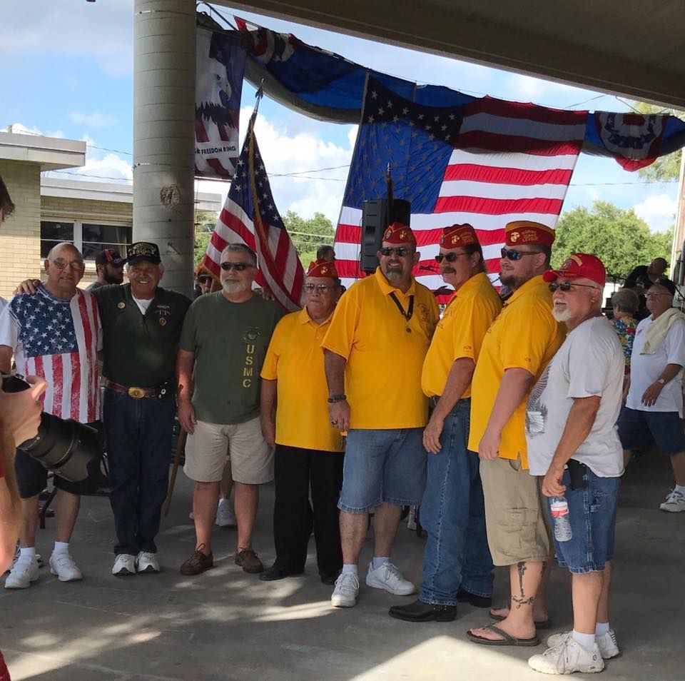 A group of men are posing for a picture in front of an american flag
