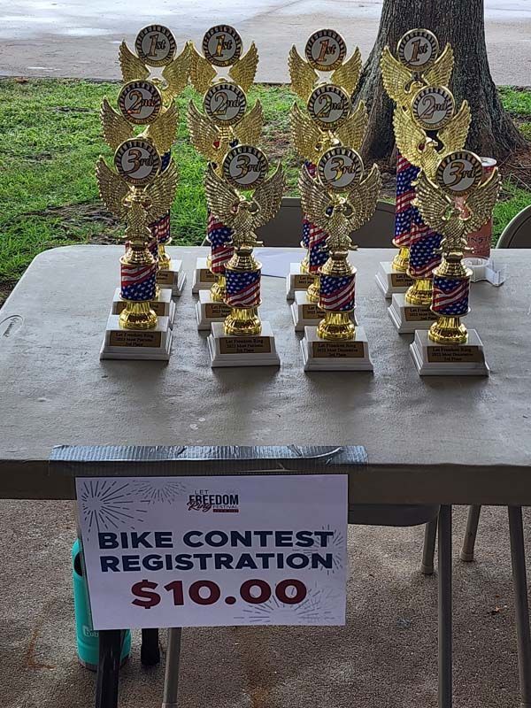 A table with trophies and a sign that says bike contest registration $ 10.00