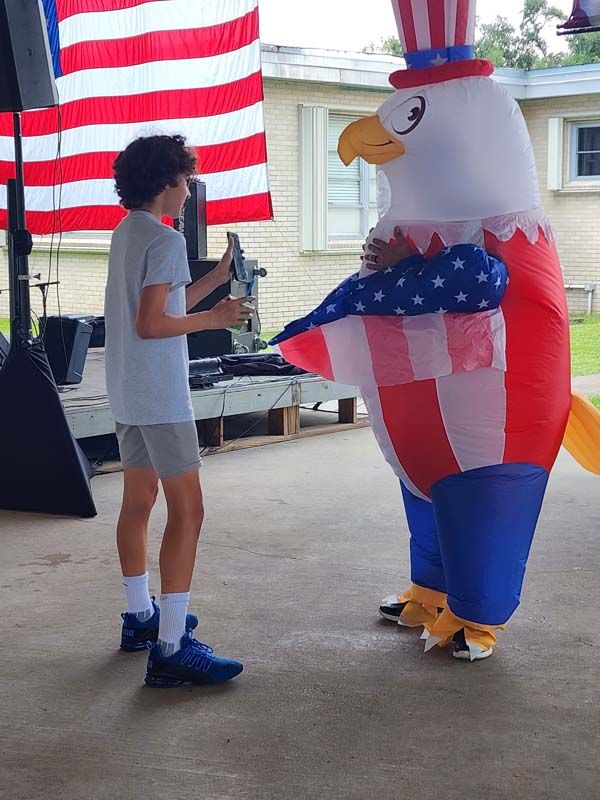 A boy is standing next to an inflatable uncle sam eagle