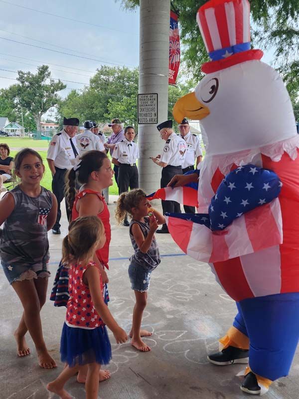 A group of children are standing around an inflatable uncle sam