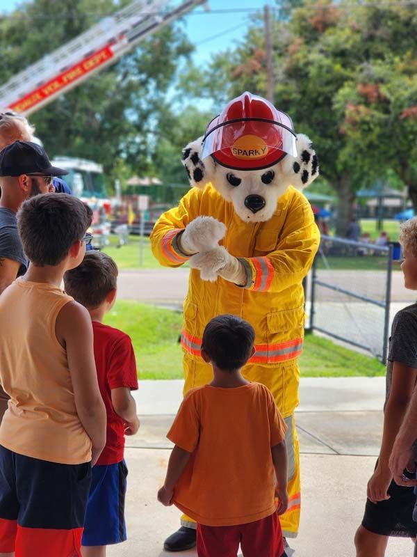 A fireman mascot is standing in front of a group of children.