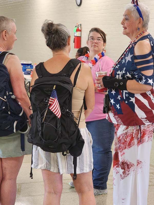 A woman with an american flag on her back is talking to a group of people