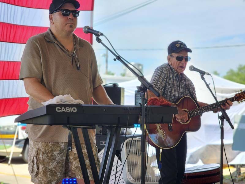 A man is playing a casio keyboard and another man is playing a guitar