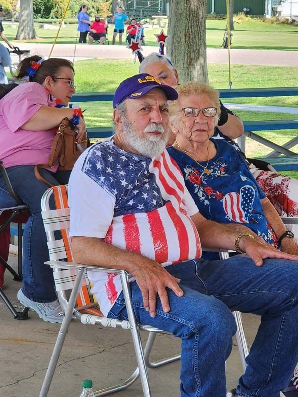 A group of people are sitting at a picnic table in a park.