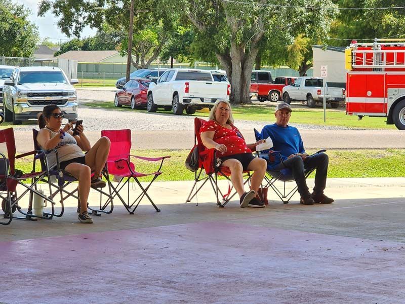 A group of people are sitting in folding chairs in front of a fire truck.