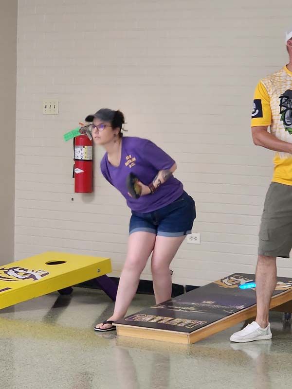 A man and a woman are playing a game of cornhole