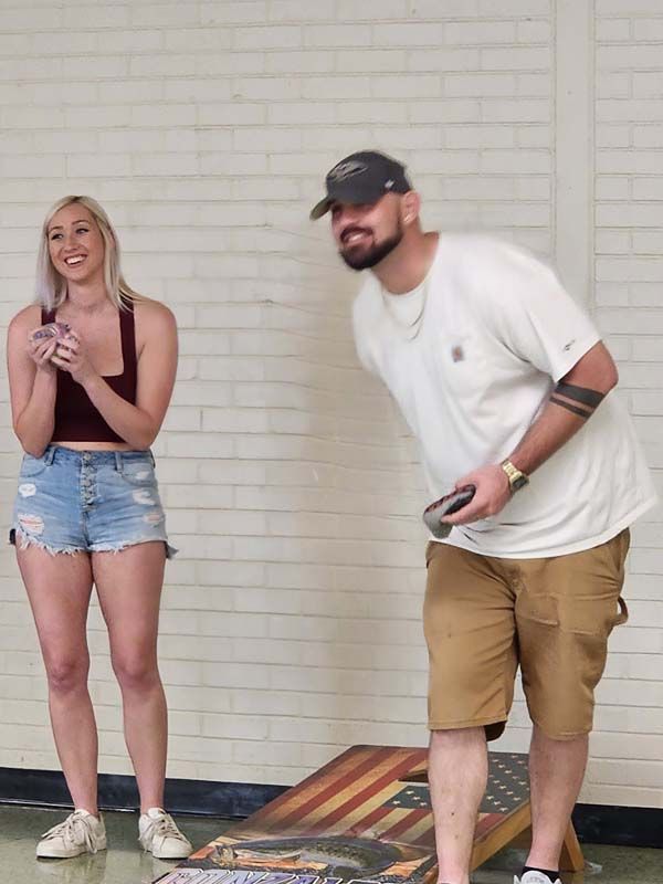 A man and a woman are playing a game of cornhole.