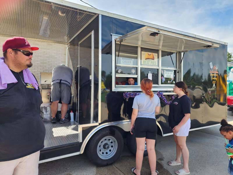 A group of people are standing in front of a food truck.
