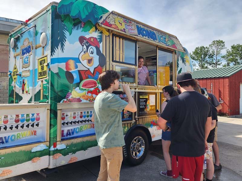 A group of people are standing in front of an ice cream truck.