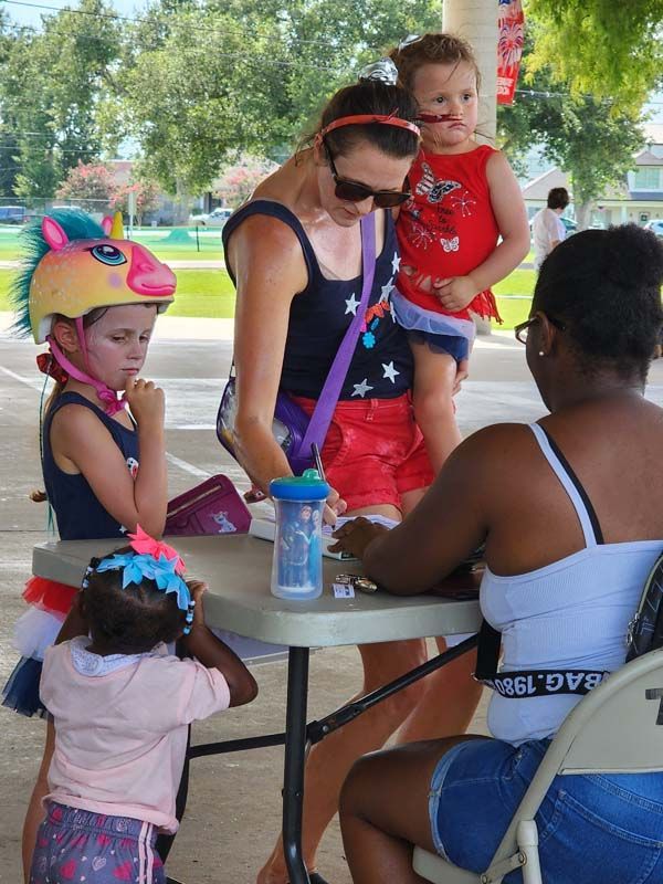 A woman is sitting at a table with two little girls and a baby.
