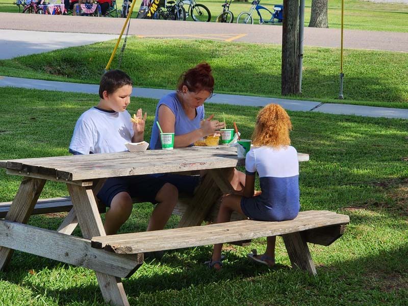A family is sitting at a picnic table eating food