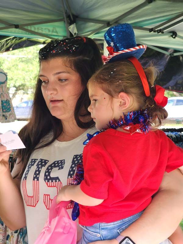woman with little girl in red shirt shopping at an outdoor booth