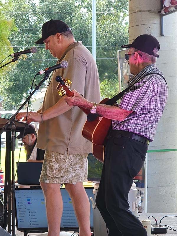 Two men are playing guitars and singing into microphones on a stage.