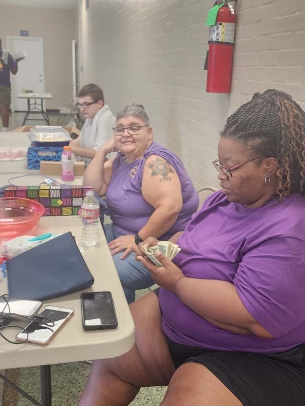 Two women are sitting at a table with a fire extinguisher in the background