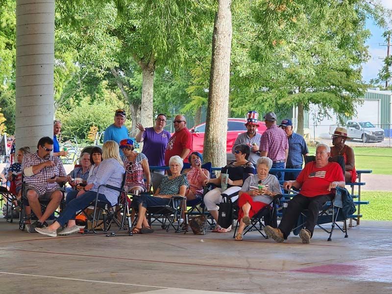 A group of people are sitting under a pavilion in a park.