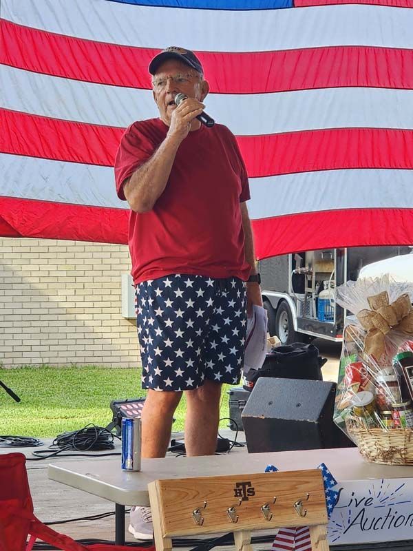 A man standing in front of an american flag holding a microphone