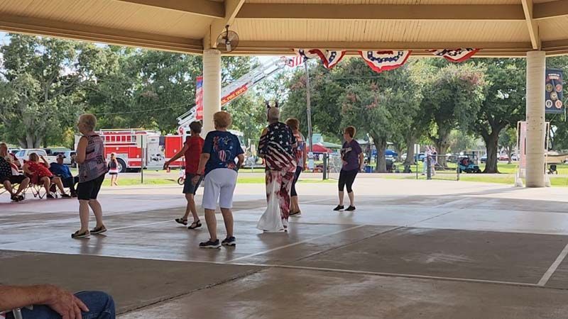 A group of people are standing under a pavilion in a park.