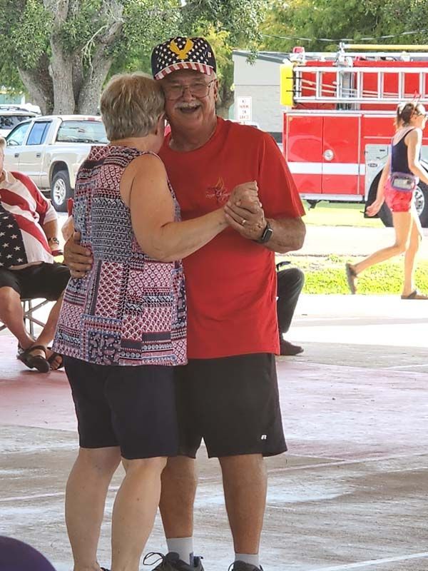 A man and woman are dancing in front of a fire truck.