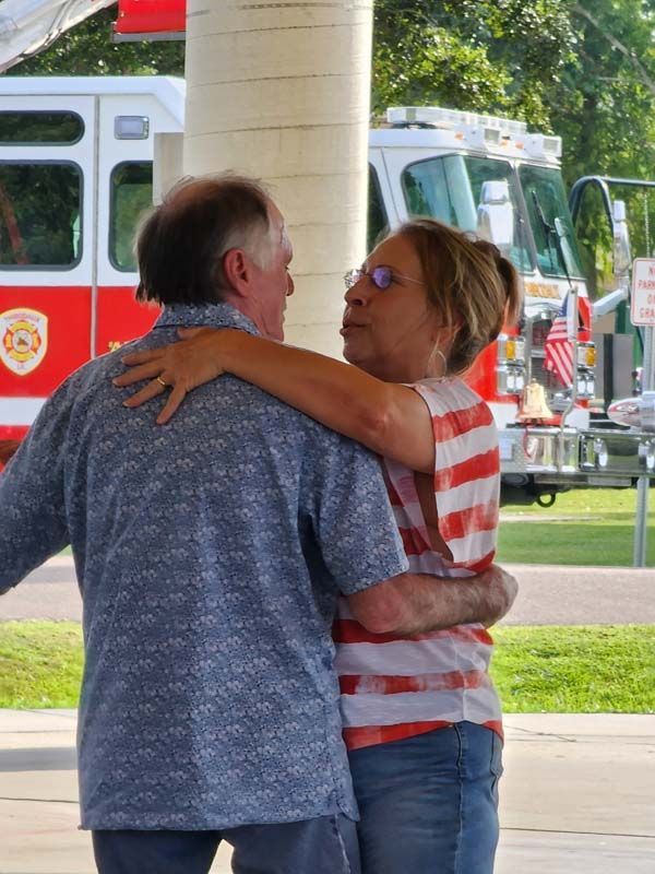 A man and woman hugging in front of a fire truck