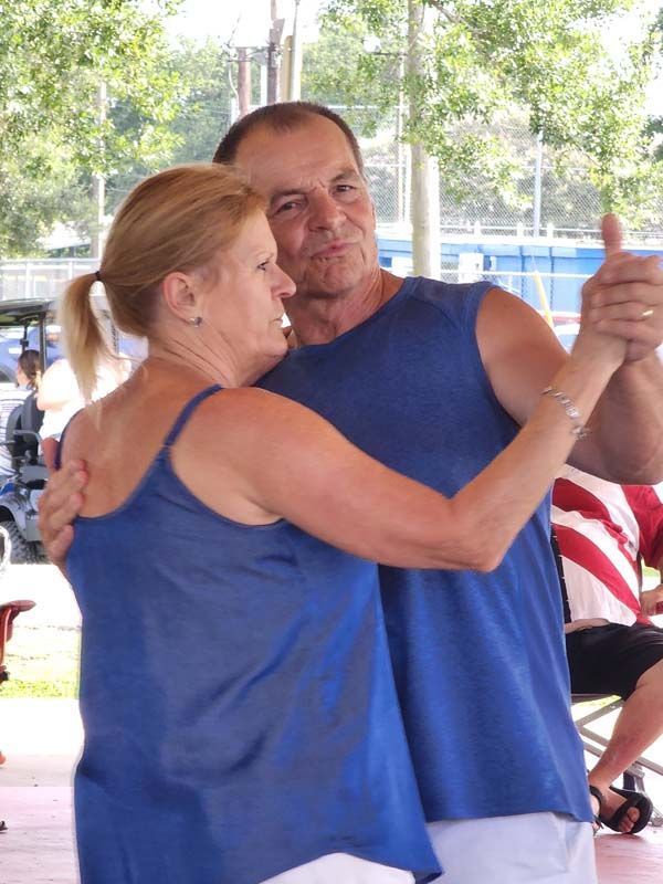 A man and a woman are dancing together and the woman is wearing a blue tank top