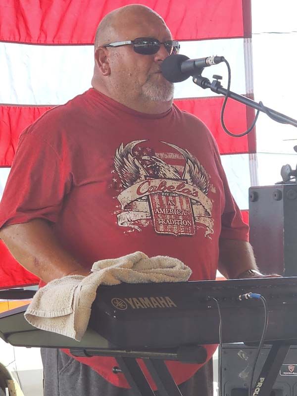 A man in a red shirt is singing into a microphone