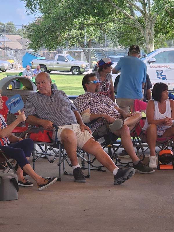 A group of people are sitting in chairs in a park.