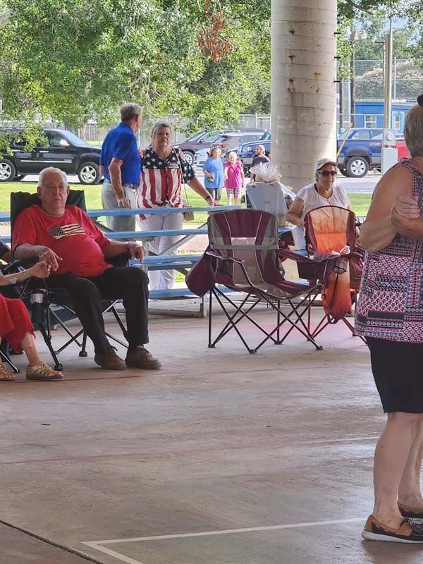 A group of people sitting in chairs under a covered area