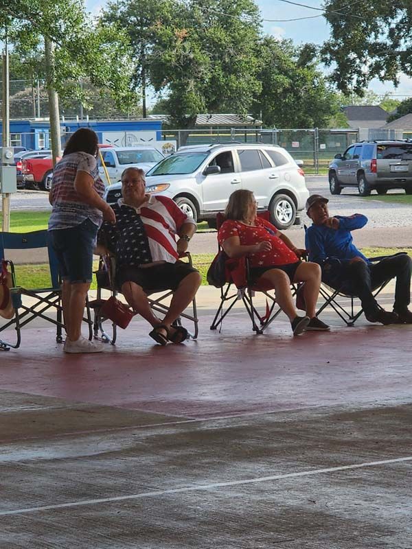 A group of people are sitting in folding chairs in a parking lot.