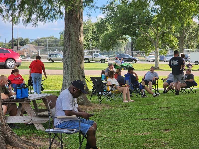 A group of people are sitting around a picnic table in a park.