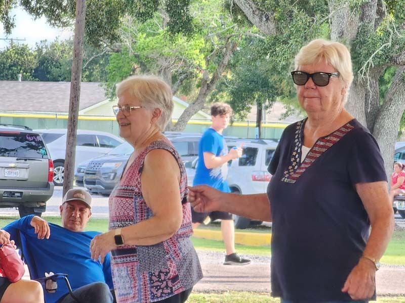 Two older women are standing next to each other in a park.