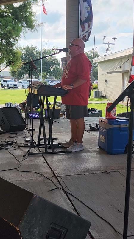 A man in a red shirt is playing a keyboard on a stage.